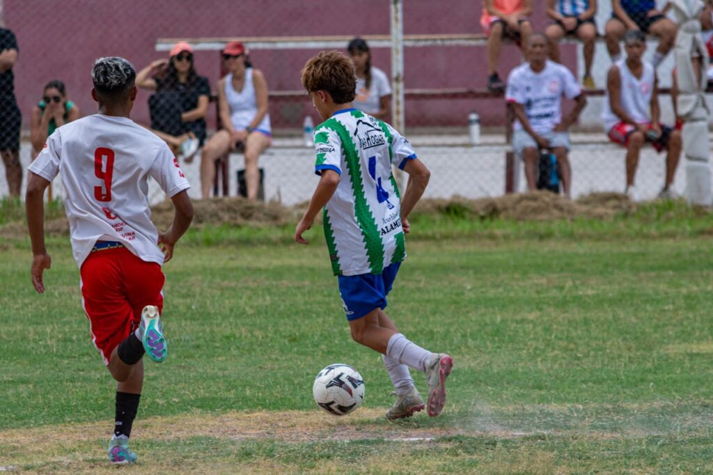 Two young soccer players competing in an outdoor match with spectators watching.
